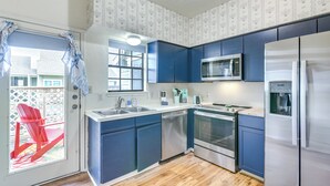 Una cocina moderna con armarios azules, electrodomésticos de acero inoxidable y suelo de madera.