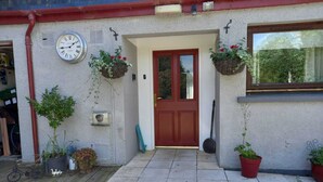 Ein Haus mit roter Tür, einer Uhr und hängenden Blumenkörben.