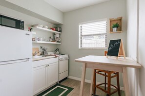 Cozinha com armários brancos, fogão, micro-ondas e um quadro negro.