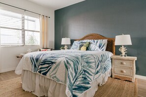 Quarto com cama, mesas de cabeceira e janela com persianas.