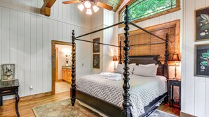 A four-poster bed with a wooden frame and a quilted bedspread, a wooden floor, a ceiling fan, and a window with a view of trees. - Group-Friendly Golf Getaway! 5 Mi to Cashiers (Cullowhee)