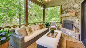 A covered porch with a stone fireplace, wicker sofa, and a dining table. - Group-Friendly Golf Getaway! 5 Mi to Cashiers (Cullowhee)