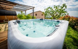 A hot tub in a backyard with a pergola, a house, and trees in the background. - Cozy home in Guardiola de Fontrubí with sauna (Guardiola de Fontrubí)