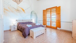 A bedroom with a bed, bedside tables, a bench, a wooden wardrobe, and a large window with a view. - Cozy home in Guardiola de Fontrubí with sauna (Guardiola de Fontrubí)