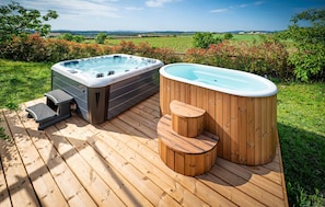 Dos jacuzzis en una terraza de madera con vistas panorámicas al campo.