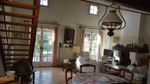 A cozy living room with a dining area, a fireplace, and a staircase. - Traditional Provencal house (Saint-Raphaël)