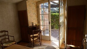 A bedroom with a bed, a desk, a chair, and a wardrobe. There is a sliding glass door leading to an outdoor area. - Traditional Provencal house (Saint-Raphaël)