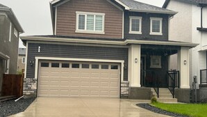 Une maison à deux étages avec un garage, un porche à l’avant et une allée.