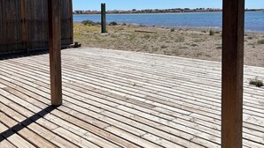Eine Holzterrasse mit freiem Blick auf ruhiges Wasser und die Ferne.