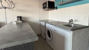 Eine kleine Küche mit Waschmaschine, Mikrowelle und Spüle.