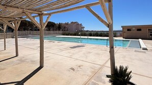 Eine Pergola aus Holz über einem Poolbereich, der von blauem Himmel überdacht wird.