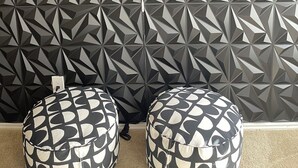 Una habitación con pared de estampado geométrico, dos otomanes estampados y un letrero de neón.