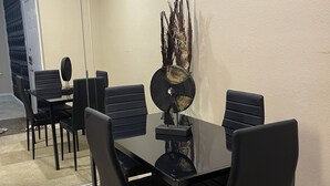 Un salón de conferencias con una mesa de cristal, sillas negras y un jarrón decorativo.