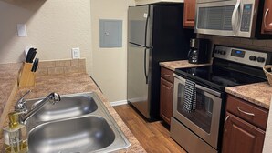 Una cocina con electrodomésticos de acero inoxidable, armarios de madera y encimera de granito.