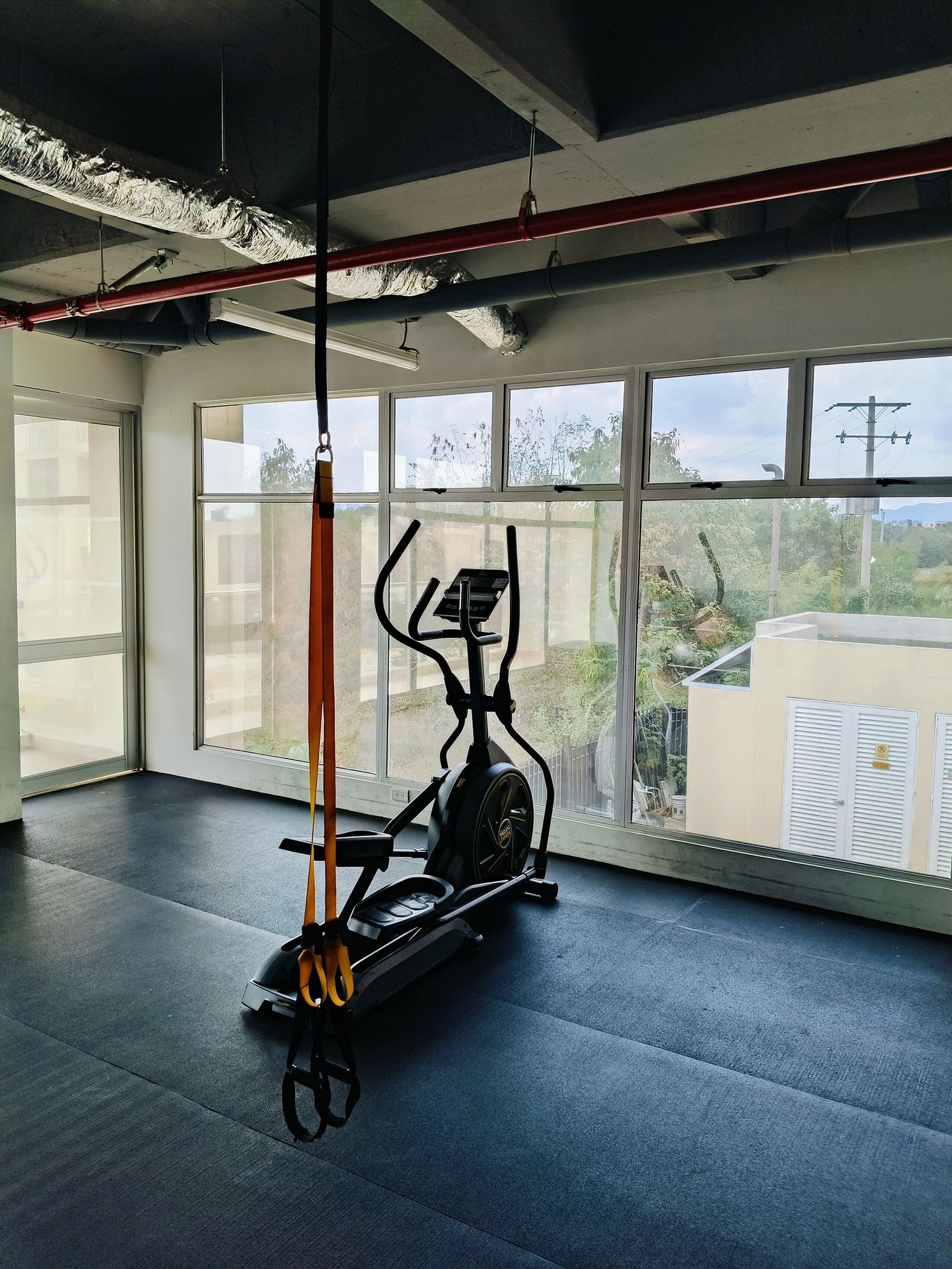 Un gimnasio con una bicicleta estática, ventanas amplias y vistas al exterior.
