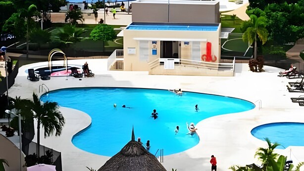 A swimming pool area with multiple pools, lounge chairs, and a building with a balcony. - Full apartment Pto Azul Club House Come and Rest (Ricaurte)
