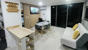A modern living room with a dining area, a TV mounted on the wall, and a sliding glass door leading to a balcony. - Full apartment Pto Azul Club House Come and Rest (Ricaurte)