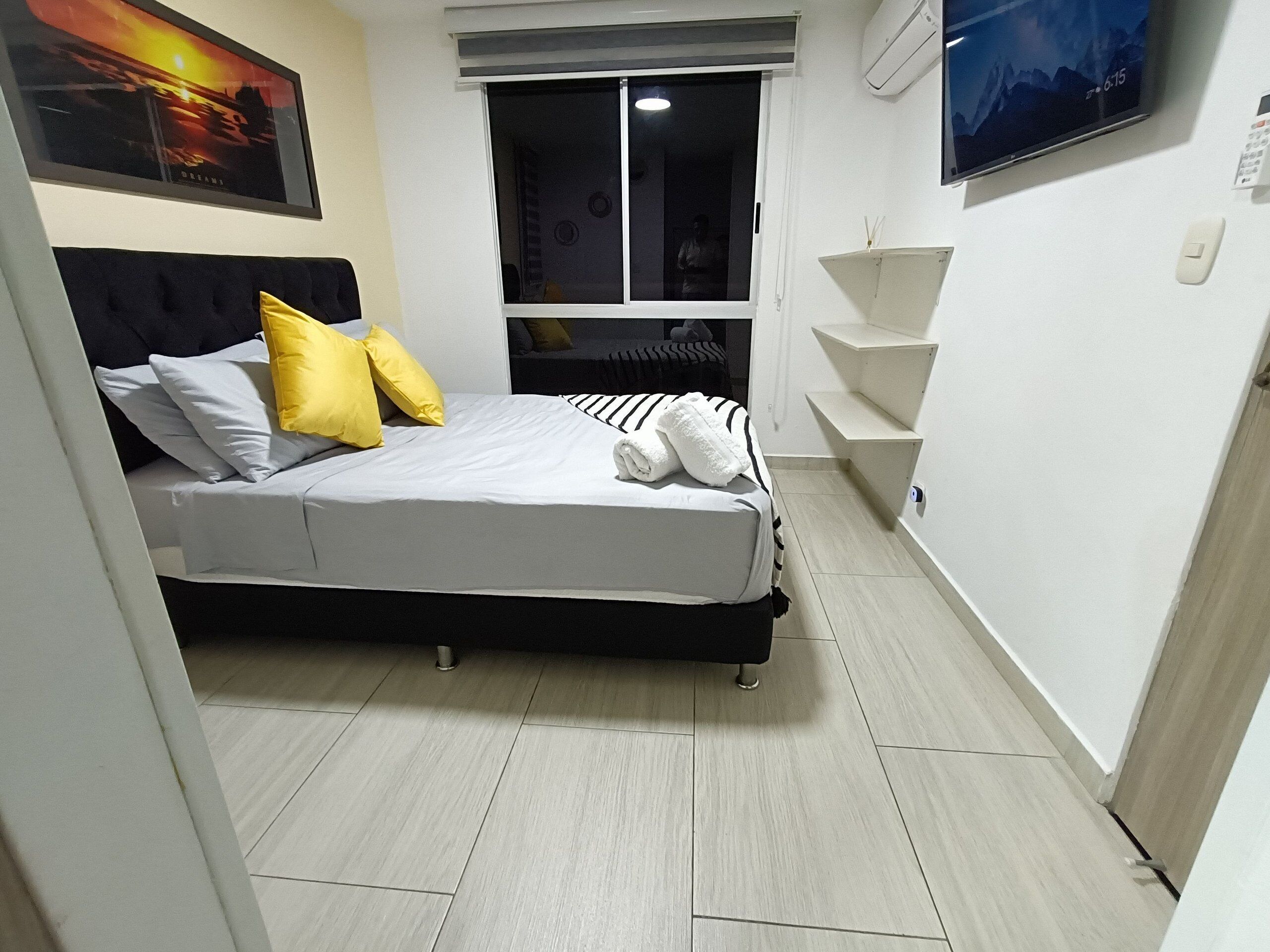 Ein modernes Schlafzimmer mit Bett, Fenster, Fernseher und einer Treppe.
