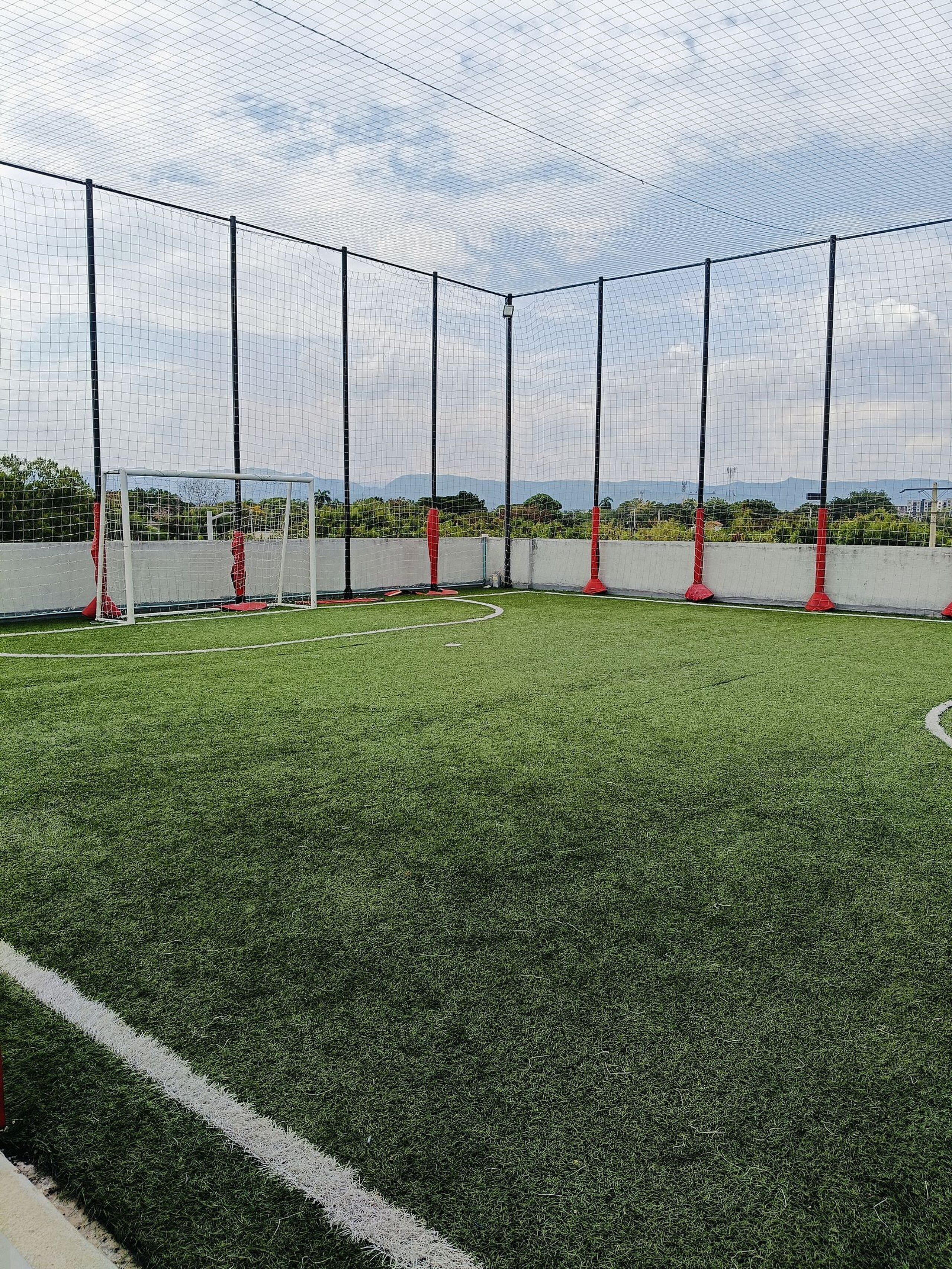 A soccer field with goalposts and a netted enclosure.