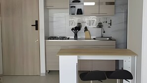 A modern kitchen with a wooden countertop, white cabinets, and a black bar stool. - Full apartment Pto Azul Club House Come and Rest (Ricaurte)
