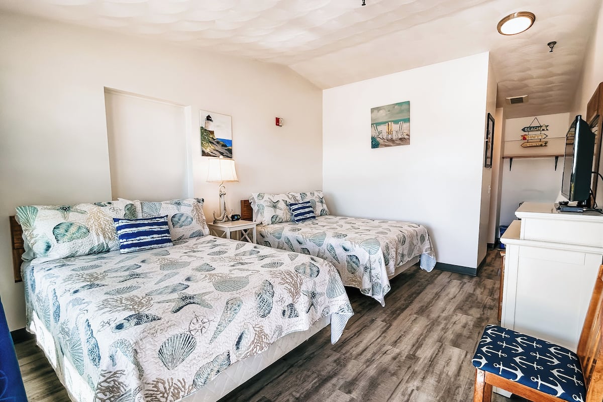 A room with two beds, a desk, and a chair.