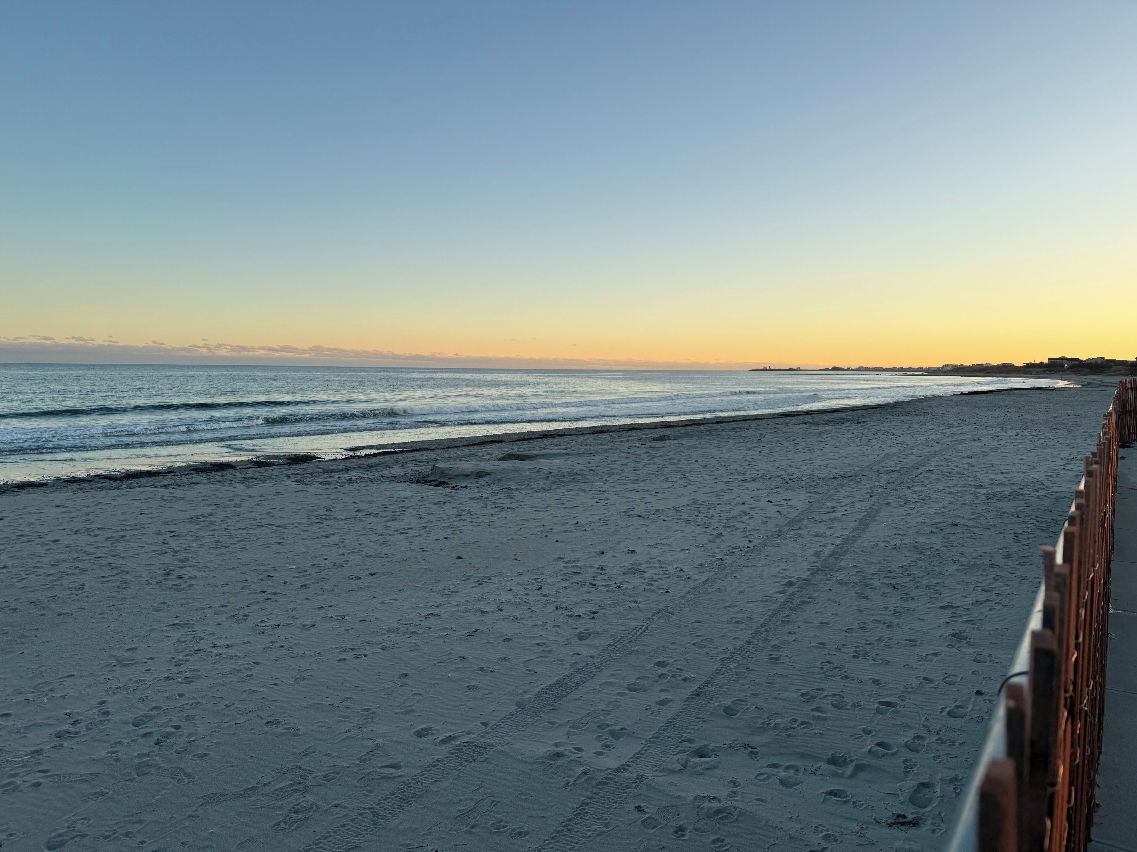 A beach with a wooden boardwalk and a clear view of the ocean.
