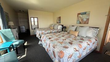A hotel room with two beds, a desk, a chair, and a window.
