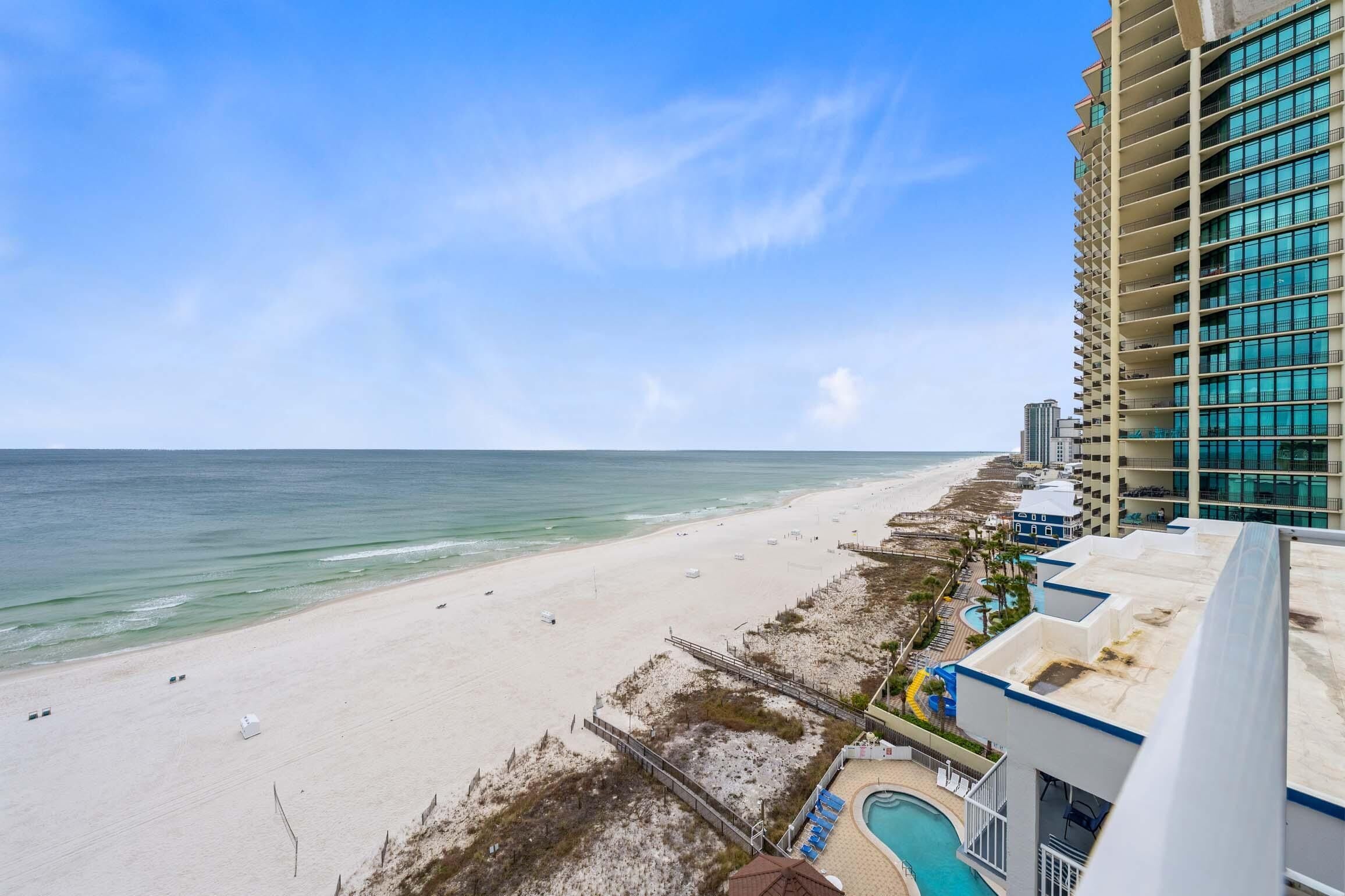 A beach view from a hotel with a pool and a high-rise building.