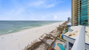 A beach view from a hotel with a pool and a high-rise building. - Romar Place 1106 (Orange Beach)