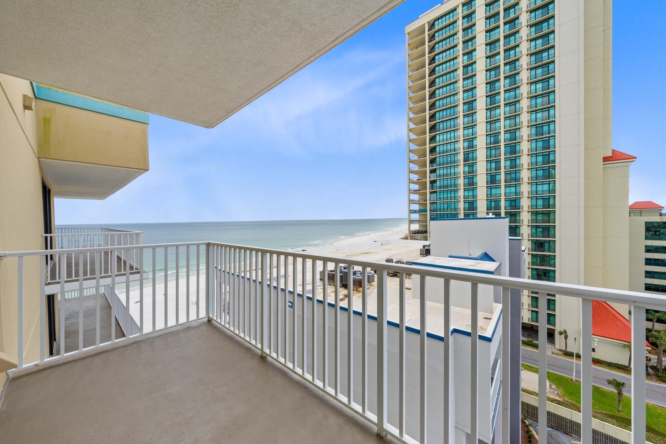 A balcony with a view of the beach and a tall building.