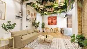 Un salon moderne avec un canapé beige, une table basse ronde et diverses plantes.