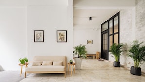 Un salon moderne avec un canapé beige, deux œuvres d’art encadrées accrochées au mur et des plantes en pot.