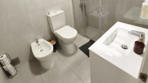 Ein modernes Badezimmer mit Toilette, Bidet und einer Duschkabine.