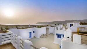 A coastal building with white walls and blue doors, featuring a flat roof and a view of the sea. - Tasguayan (Tafedna)