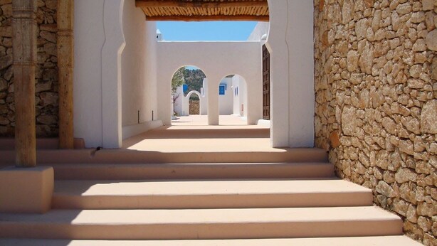 A pathway leading to a building with white walls and stone pillars. - Tasguayan (Tafedna)