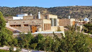 A traditional stone building with a wooden door, a stone staircase, and a view of a hilly landscape. - Tasguayan (Tafedna)