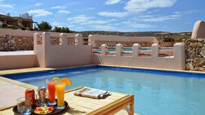 A pool area with a table set for a meal, a drink, and a newspaper. - Tasguayan (Tafedna)
