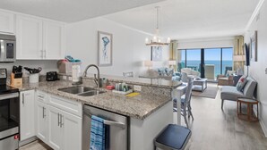 A modern kitchen with granite countertops, stainless steel appliances, and a central island. - September Dates Available! Tropical Winds 703! (Gulf Shores)