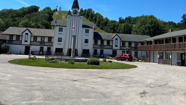 A large building with a central tower, multiple balconies, and a parking lot. - Schuss Village Studio Unit 117 True Ski-in/Ski-out. (Bellaire)