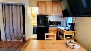 A compact kitchen with wooden cabinets, a black refrigerator, a microwave, and a coffee maker. - Schuss Village Studio Unit 117 True Ski-in/Ski-out. (Bellaire)