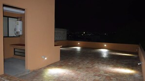 A rooftop terrace with a water heater, a small table, and a bench.
