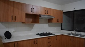 A kitchen with wooden cabinets, a gas stove, a black speaker, and a window.