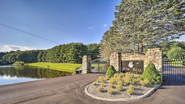 A golf club entrance with a stone archway, a pond, and a well-maintained lawn. - Olde Beau Golf / Blue Ridge Mountains Golf / Resort 1BR 1BA Condo PET FRIENDLY!! (Roaring Gap)