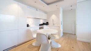 Una cucina moderna con mobili bianchi, un tavolo da pranzo rotondo e sedie bianche.