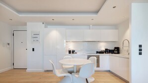 Una cucina moderna con mobili bianchi, un tavolo da pranzo rotondo e un forno a incasso.