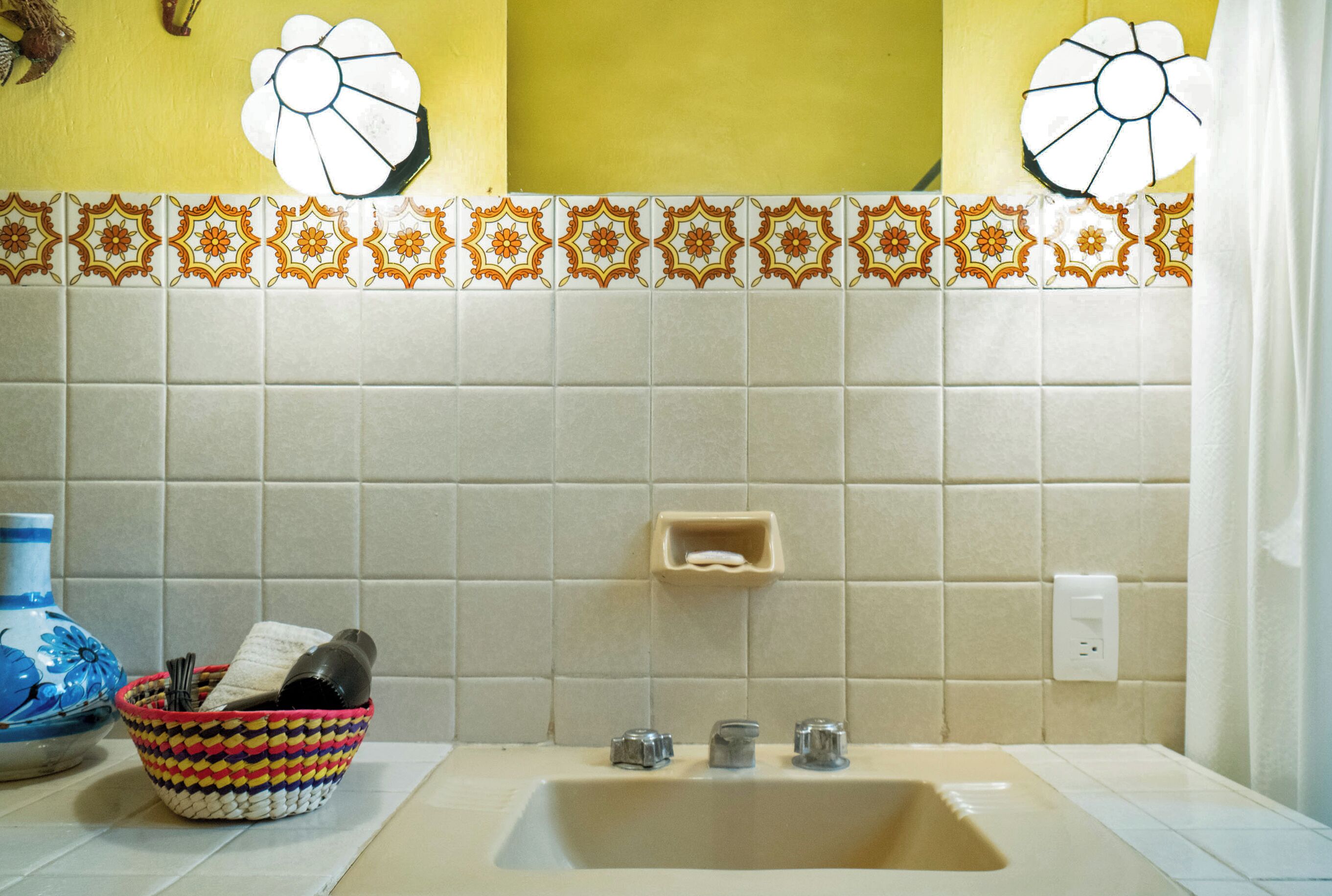A bathroom with a sink, a soap dish, and a decorative tile backsplash.