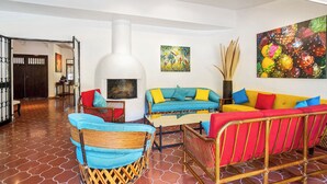 A living room with a fireplace, colorful sofas, and a large fruit painting. - Garden of Dreams Boutique Hotel (Chapala)