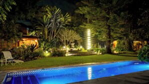 A swimming pool surrounded by lush greenery and a well-lit patio area. - Garden of Dreams Boutique Hotel (Chapala)