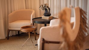 A room with two beige armchairs, a small round table with a vase of dried flowers, and a book. - Morada Pedra Branca  (Balneário Camboriú)