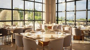 A modern dining area with large windows, round tables, and comfortable seating. - Morada Pedra Branca  (Balneário Camboriú)